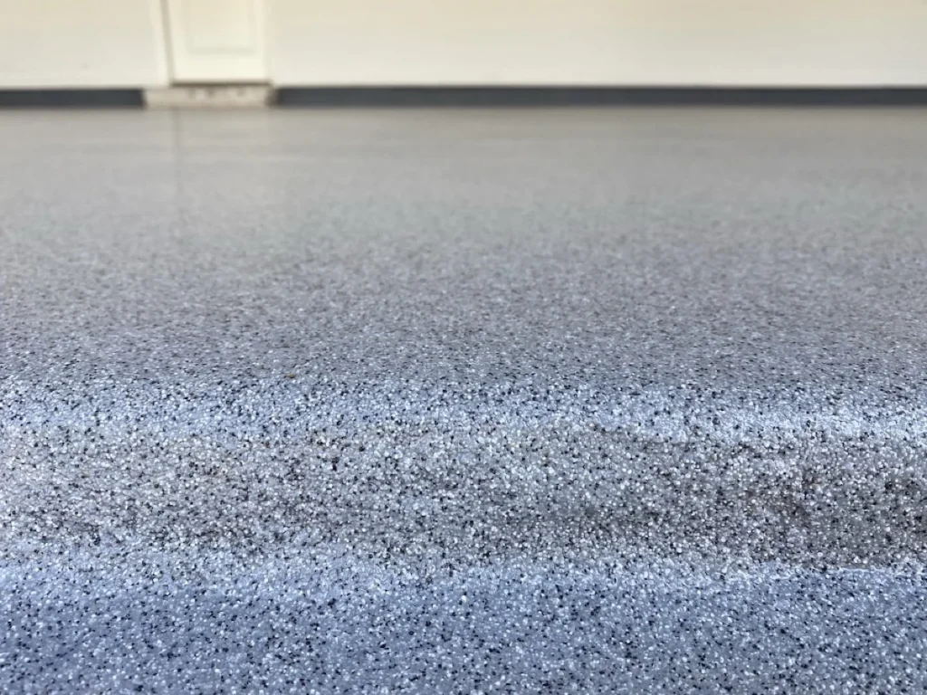 Close-up of a quartz garage floor in Albuquerque by 505 Garage Floors, showing the textured, slip-resistant quartz broadcast finish.